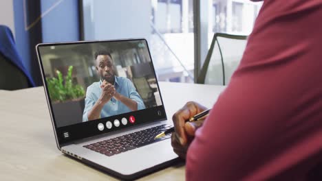 Hombre-Afroamericano-Usando-Una-Computadora-Portátil-Para-Videollamadas,-Con-Un-Colega-De-Negocios-En-La-Pantalla