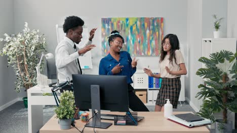 dance at work, office, break from duties, company party, two girls and a man in a shirt and tie dancing together, fooling around, laughing, smiling, relieving stress, music playing from the computer