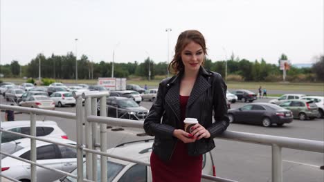 young woman with coffee in a parking lot
