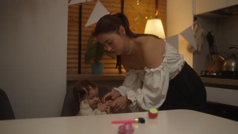 mother dressing baby daughter at a birthday party in the kitchen