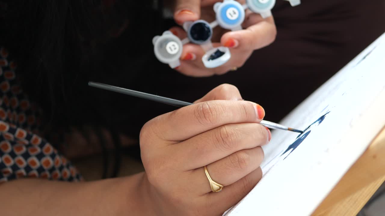 mujer pintando con acrílicos en lienzo