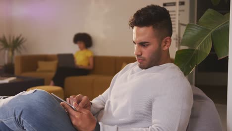 hombre de raza mixta en un teléfono inteligente en la oficina creativa