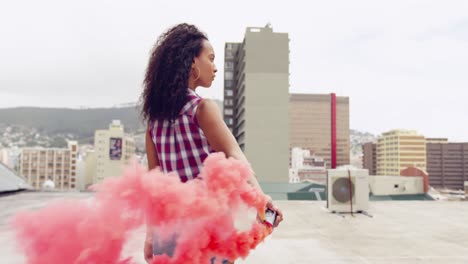 Fashionable-young-woman-on-urban-rooftop-using-a-smoke-grenade