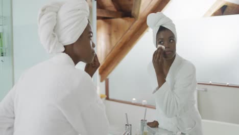 african american attractive woman removing make up in bathroom