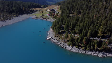 Fantastica-Toma-Aerea-En-Orbita-Sobre-El-Lago-Oeschinen-Y-Viendo-El-Hermoso-Bosque-Que-Lo-Rodea,-En-Un-Dia-Soleado-Y-Apreciando-Las-Aguas-Turquesas