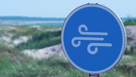 blue high wind sign at liepaja beach dunes in hot sunny day, close up shot