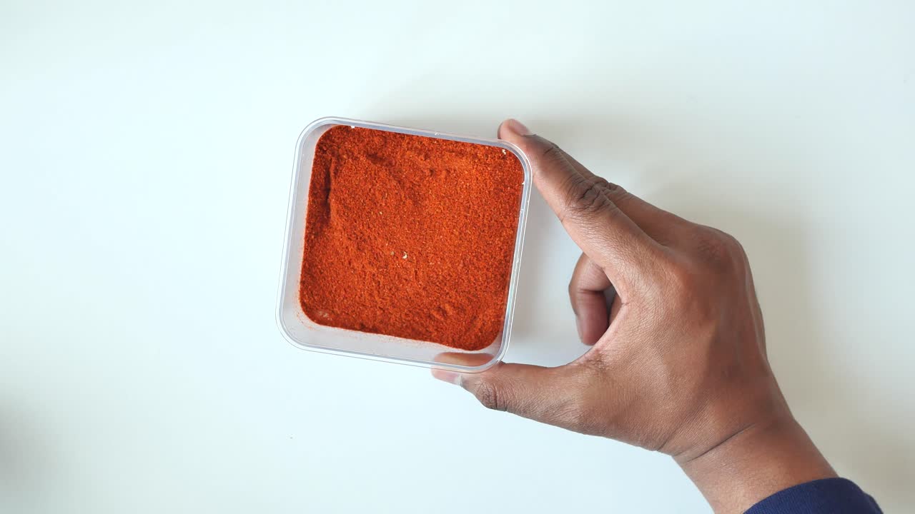 칠리 가루 를 담은 용기 를 들고 있는 손