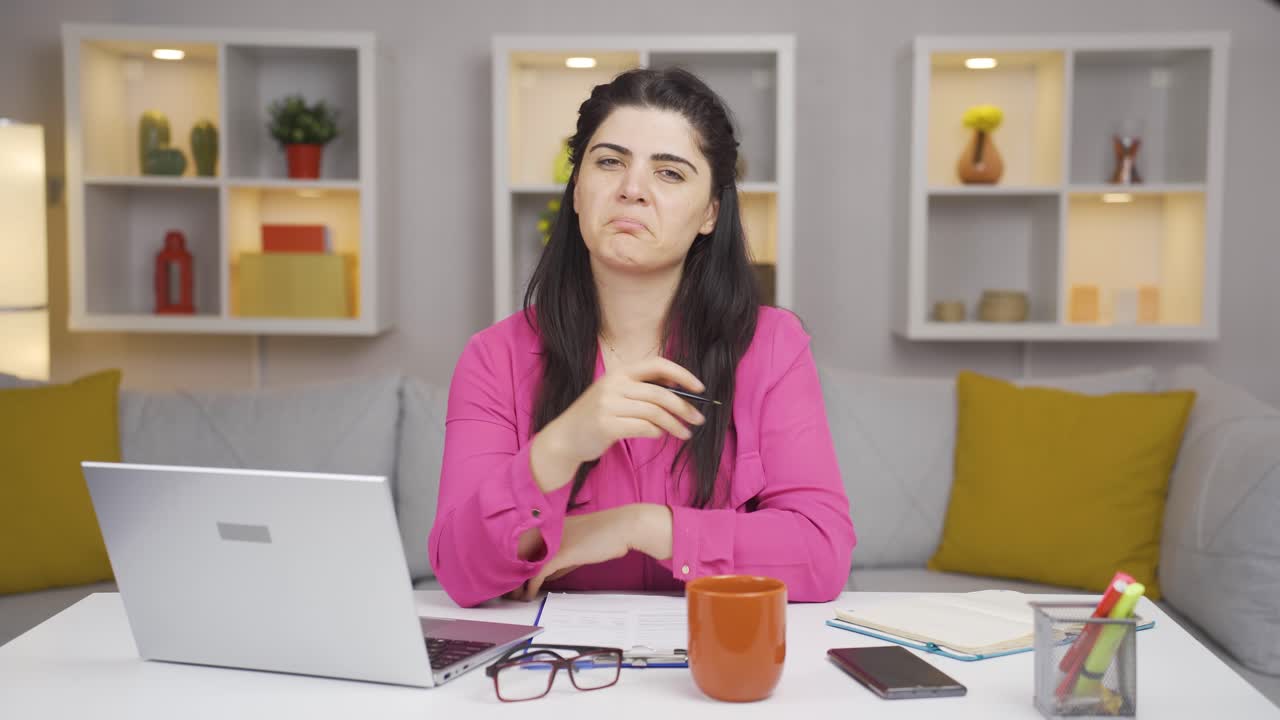 una mujer que trabaja en una oficina en casa asiente con la cabeza a la cámara.