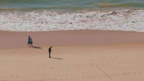 Hombre-Ignorando-El-Mundo-Que-Lo-Rodea,-Usando-Su-Teléfono-En-La-Playa