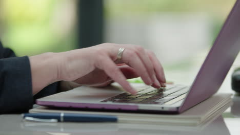 cerca de las manos de las mujeres trabajando en una computadora portátil en la oficina de casa