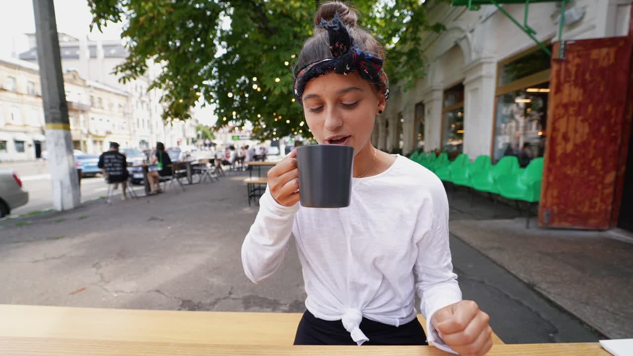 una adolescente bebiendo café al aire libre