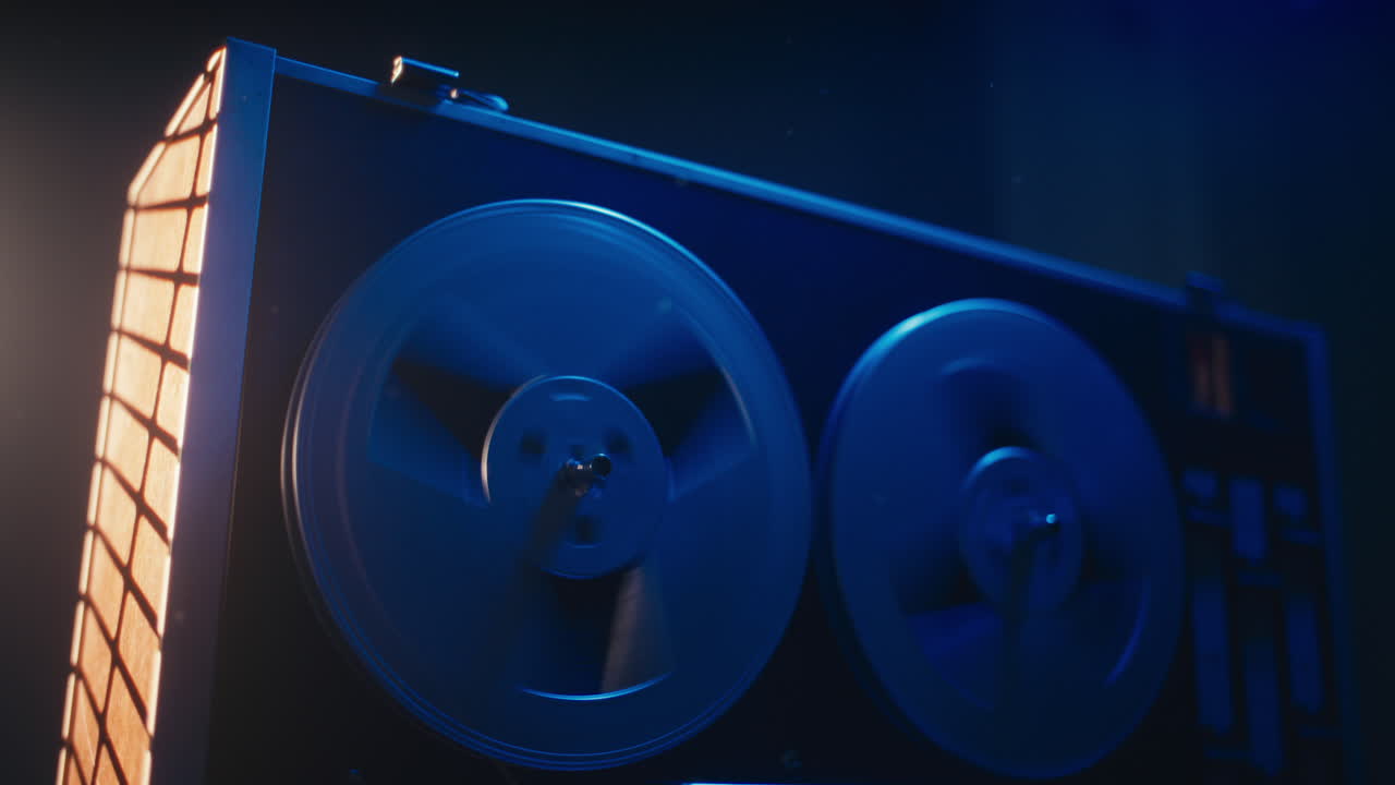 A vintage tape recorder spinning spools in a blue light