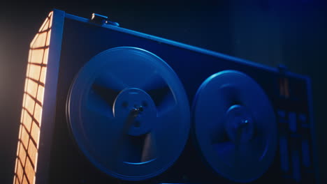 a vintage tape recorder spinning spools in a blue light