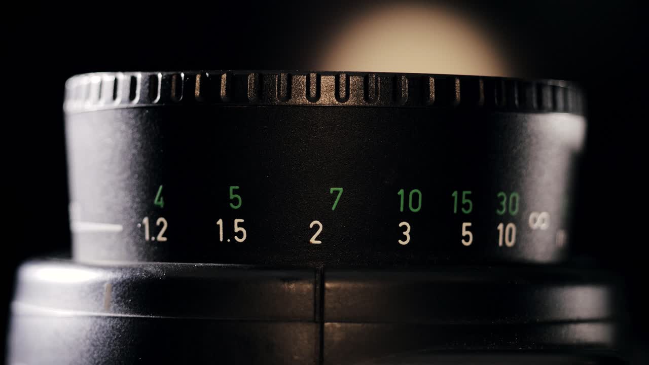 Backlit front view of focus ring with feet and meters turning back and forth adjusting focus distance