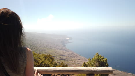 a woman with her back turned, admires the spectacular landscape that can be seen from the la peña viewpoint on the island of el hierro on a sunny day