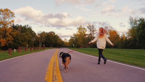 A-young-woman-walking-her-dog---an-Australian-Shepherd