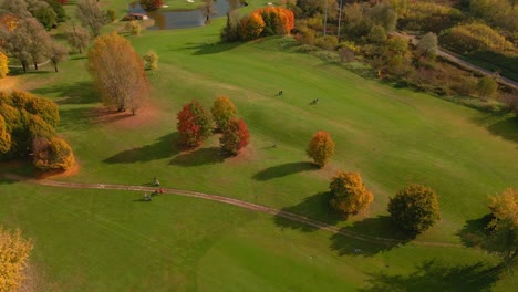 Jugadores-De-Golf-Caminando-Sobre-Hierba-Bellamente-Cuidada-En-Un-Campo-De-Golf-En-Otoño---Toma-Aérea-Panorámica