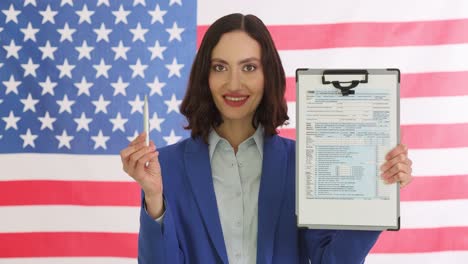 woman holds 1040 tax form in front of american flag