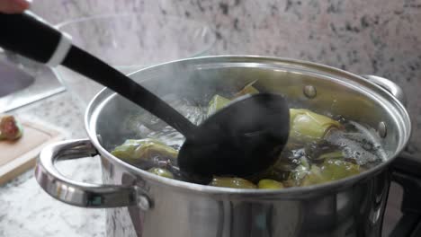 boiling and cooking artichokes in saucepan, closeup in kitchen