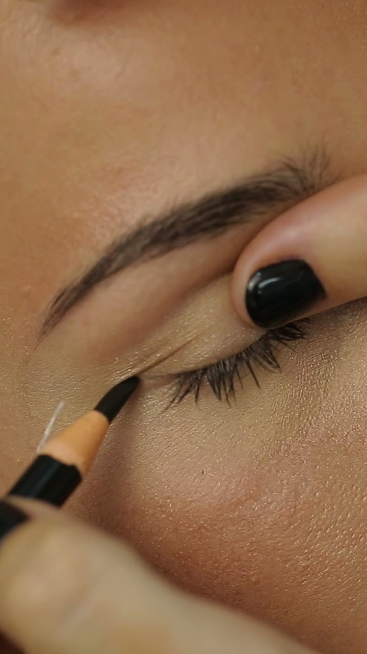 Woman Lying On Couch At Beauty Salon. Cosmetologist making eyeliner permanent make up