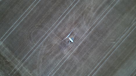 Spinning-birds-eyes-view-of-a-small-wind-turbine-in-a-farmers-field