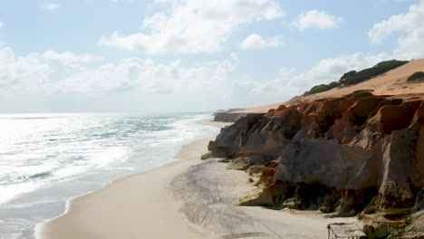 Aerial-view-of-Morro-Branco-beach,-from-the-cliff-to-the-sea,-Ceara,-Brazil