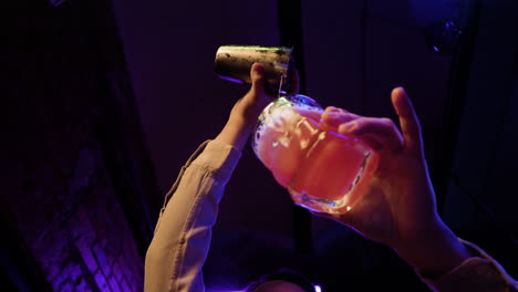 bartender schenkt cocktail in een glas.