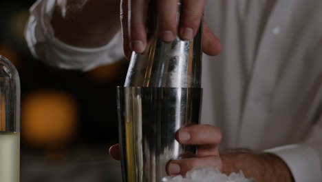 bartender shutting a cocktail shaker and beginning to shake