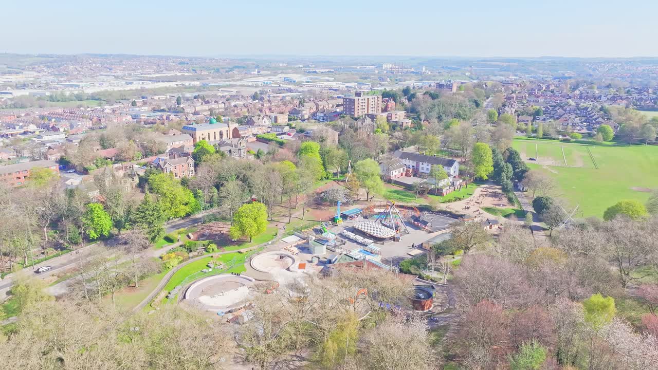 Open grass field beside tree line and curved paths seen in springtime aerial, outskirts of Clifton Park UK
