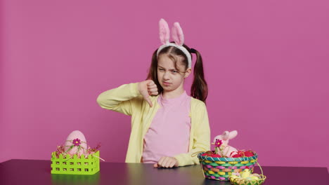 displeased unhappy child giving thumbs down in studio