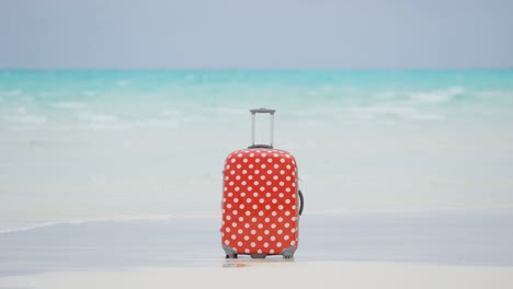 maleta de viaje colorida en una playa de arena blanca