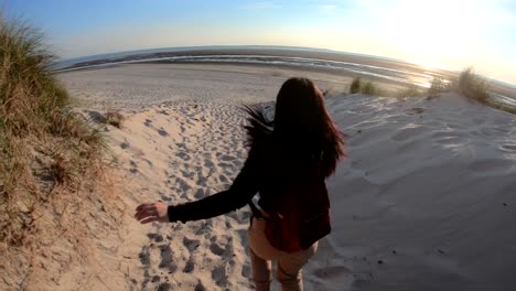 Girl-with-camera-running-on-the-beach-and-turning-her-head-to-the-camera-close-up-in-slow-motion