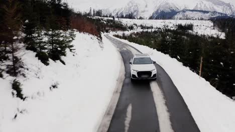 Coche-Blanco-Conduciendo-Por-Una-Carretera-De-Montaña-Nevada-En-Invierno---Disparo-De-Drones