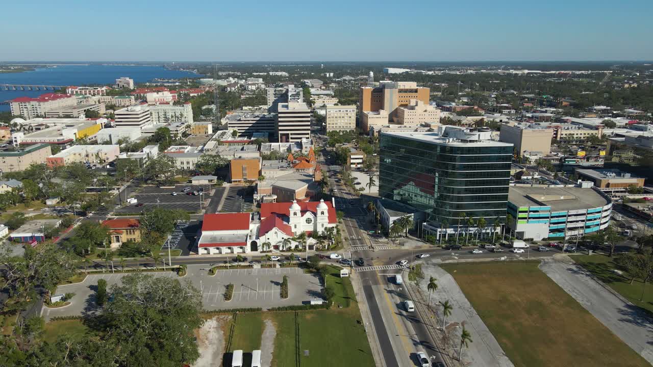 Aerial drone view of downtown Bradenton Florida showcasing buildings, and surrounding cityscape under clear blue skies. Crane Down E