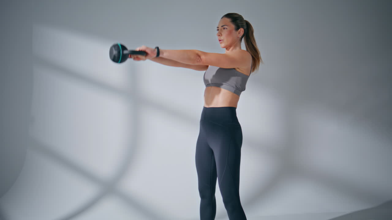 Personal trainer exercising kettlebell at indoor health club. Strong lady sport