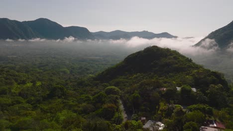 drone flies above countryside mountains landscape in panama during sunrise, foggy morning with clouds, el valle de anton crater