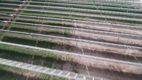 volando rápido y bajo sobre filas horizontales de paneles solares fotovoltaicos en una instalación de energía verde