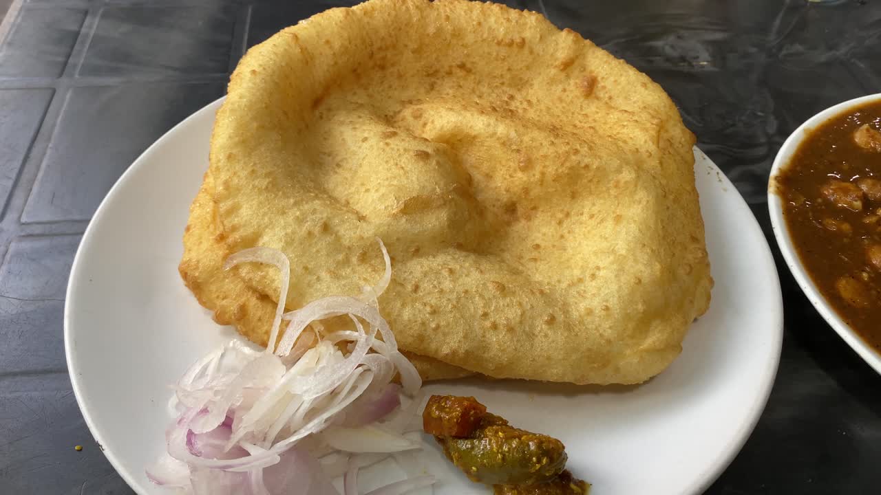 video de pan de desayuno indio chole bhature o poori con curry chana masala de garbanzos, sabroso plato indio hecho con harina de trigo para todo uso servido con pepinillos mixtos y cebolla en rodajas