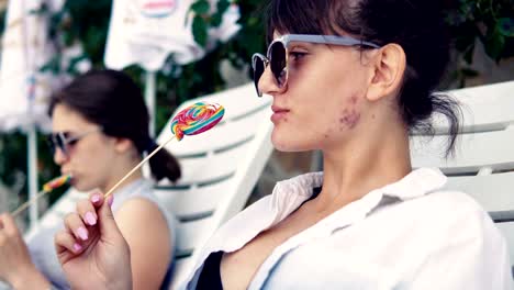 happy teen girls licking lollipop on the beach and enjoying the music and the sun