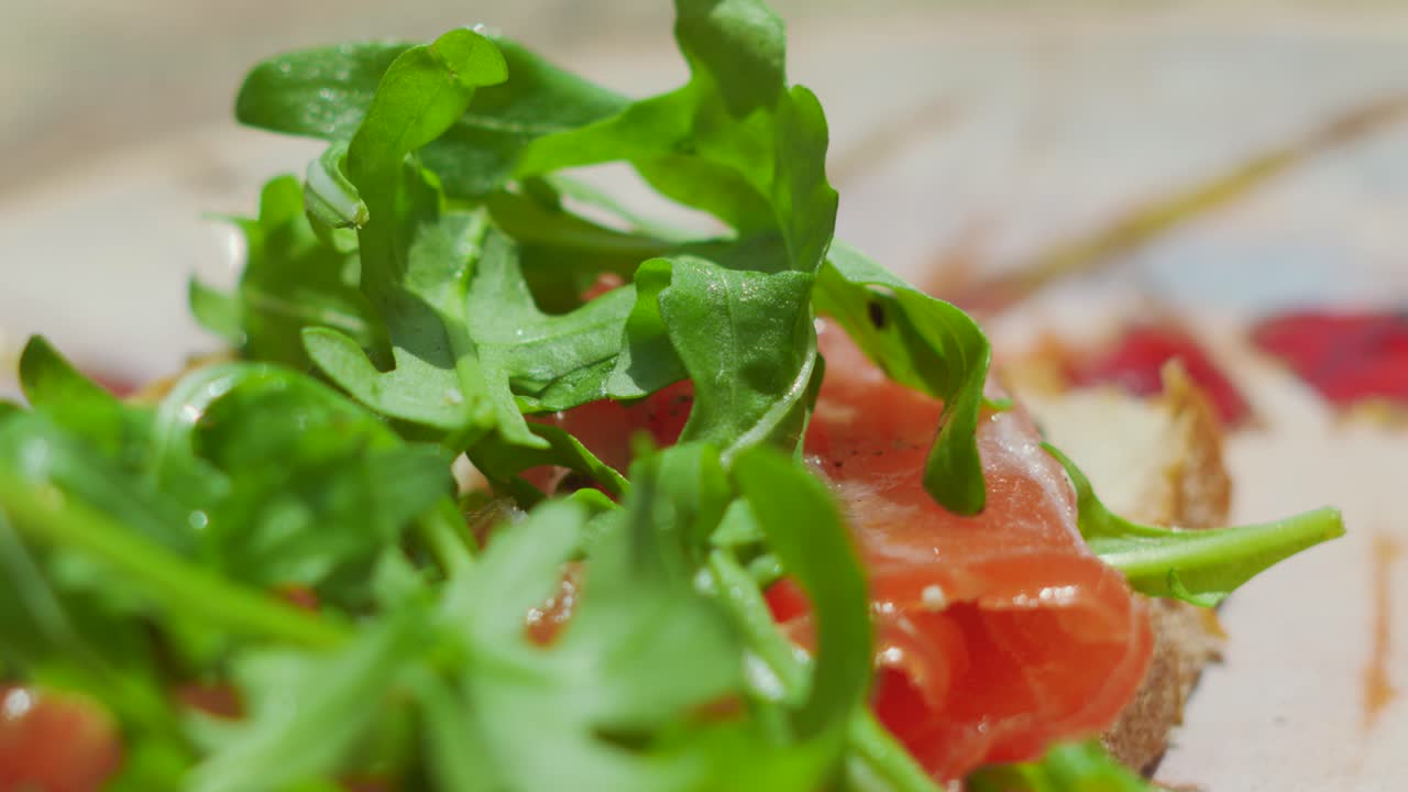 Smoked Salmon on Fresh Bread with Rocket Salad in Natural Sunlight. Summer Seafood Seasoned with Cracked Black Pepper.