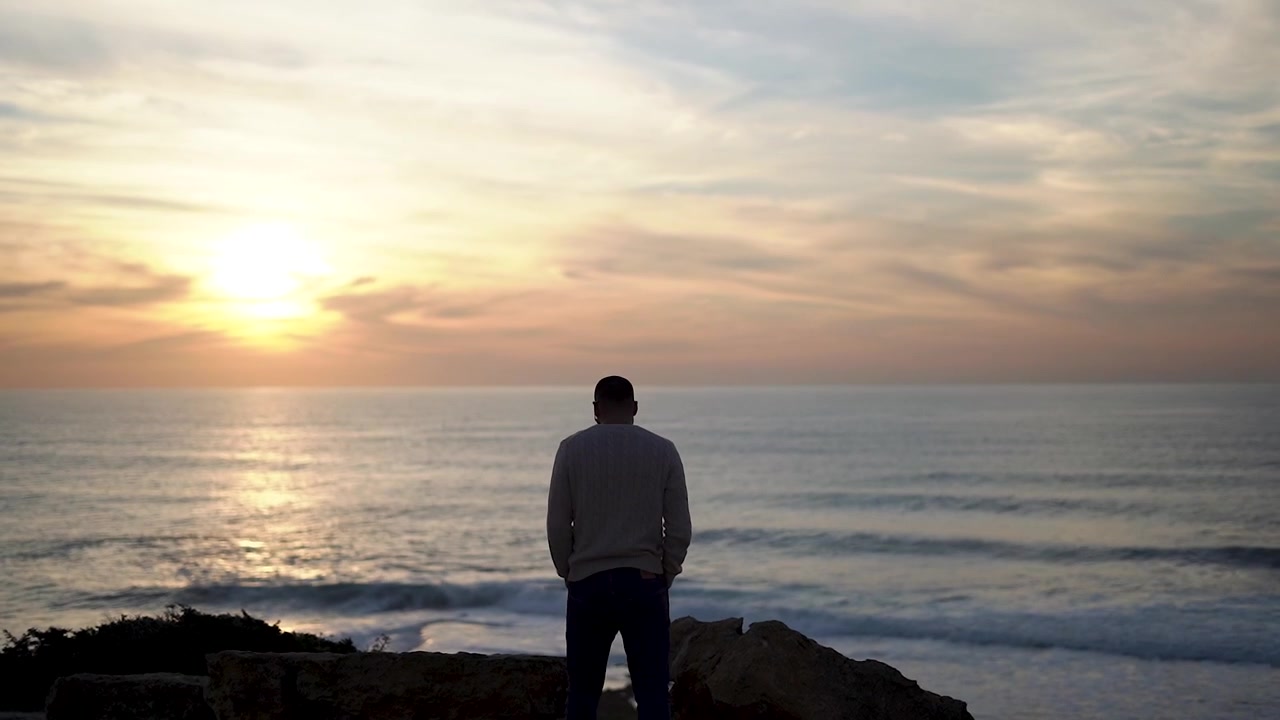 Silhouette maschile giovane che guarda il mare, godendosi il tramonto, viaggio lungo la costa