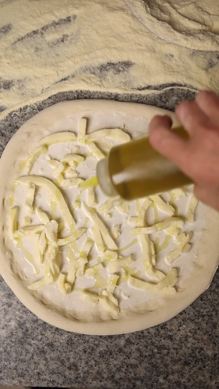 Un filo d'olio d'oliva sull'impasto della pizza con formaggio