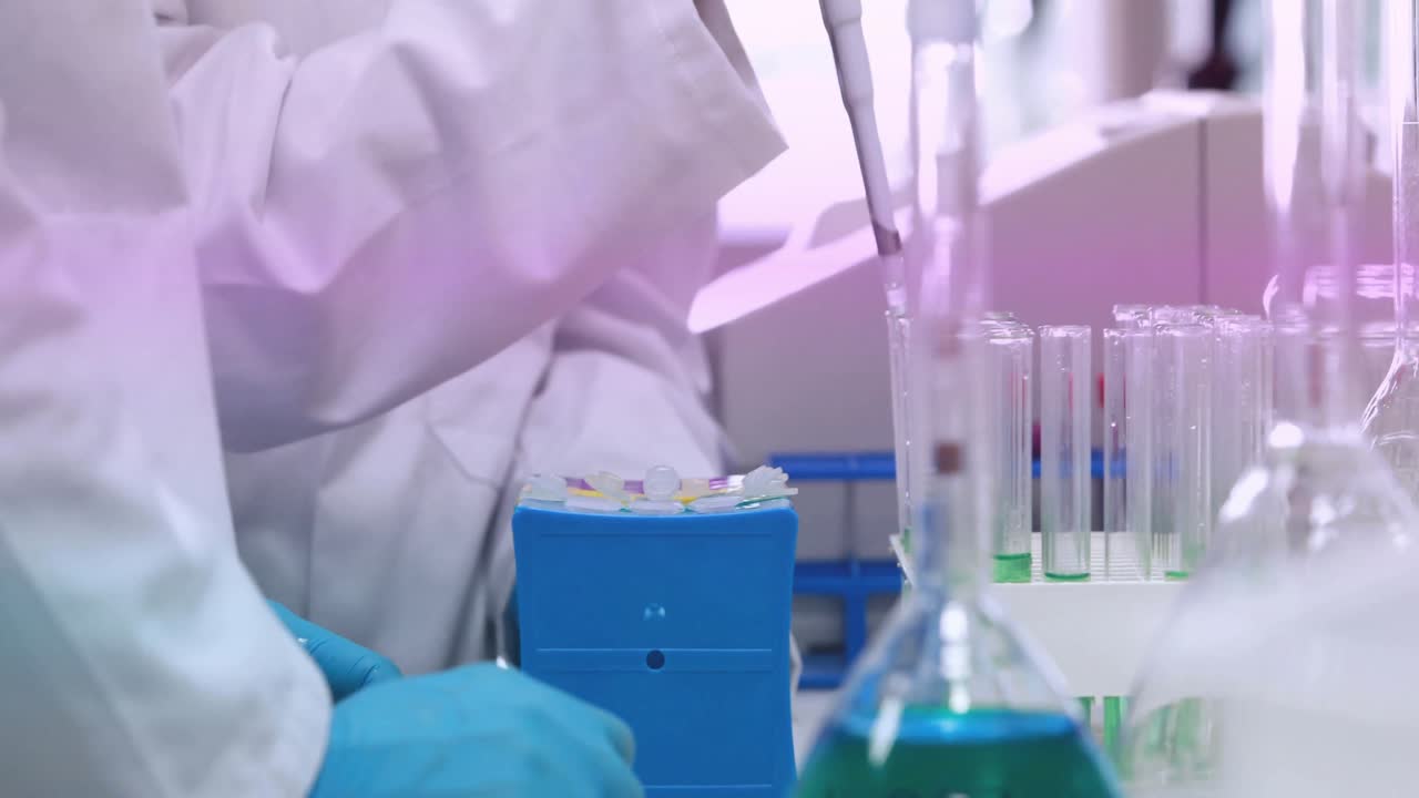 Female scientist picking up micropipette at lab bench, aspirating sample and dispensing into rack