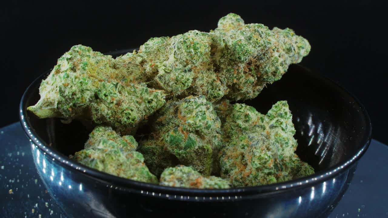 녹색 말린 마리화나 새싹은 개념 샷을 닫고 말린 마리화나 식물 더미, 주황색 트리코메스 균주, 작은 검은색 반짝이는 외침, 회전 스탠드, 스튜디오 조명, 느린 동작, 4k 비디오
