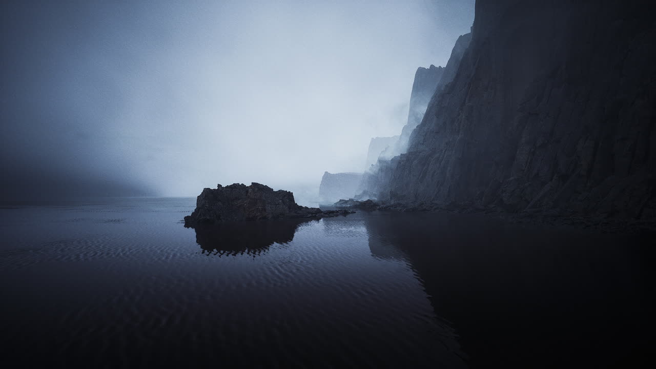 Misty cliffs reflected in calm water at dusk in a serene coastal landscape