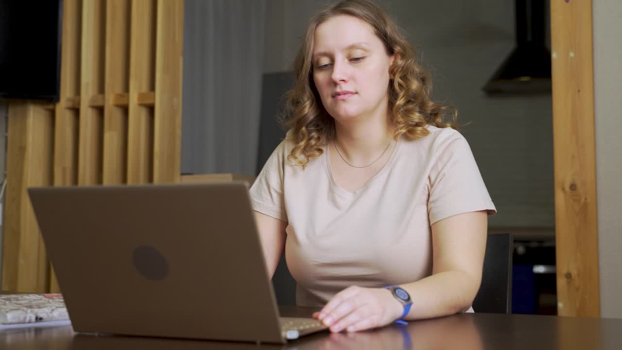 la mujer se sienta en su escritorio, abre su portátil, bloc de notas y comienza a trabajar. el comienzo de la jornada laboral. e-learning, trabajo remoto en un portátil a través de internet, trabajo en casa, distancia, pandemia