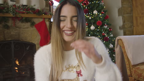 young woman holding glass of champagne and talking to camera during christmas video call