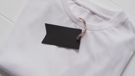 Video-of-flat-lay-of-white-t-shirt-with-tag-and-copy-space-on-white-background