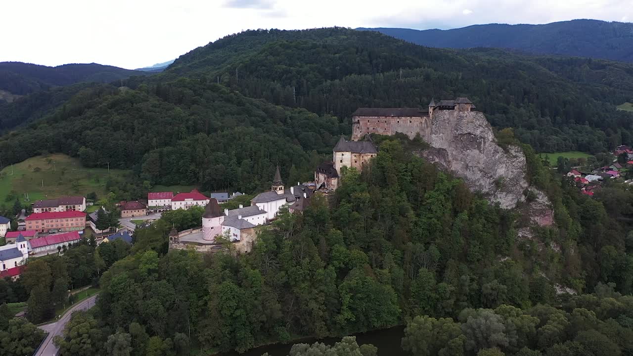 A drone orbits grand Orava Castle, showcasing its imposing medieval towers and stone ramparts set high above the lush Slovak landscape