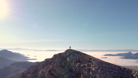 Hiker-standing-on-top-of-a-mountain-drone-shot